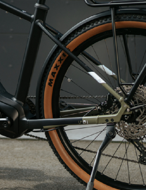 Detailansicht eines E-Bike-Hinterrads mit Schutzblech und braunem Reifenprofil.